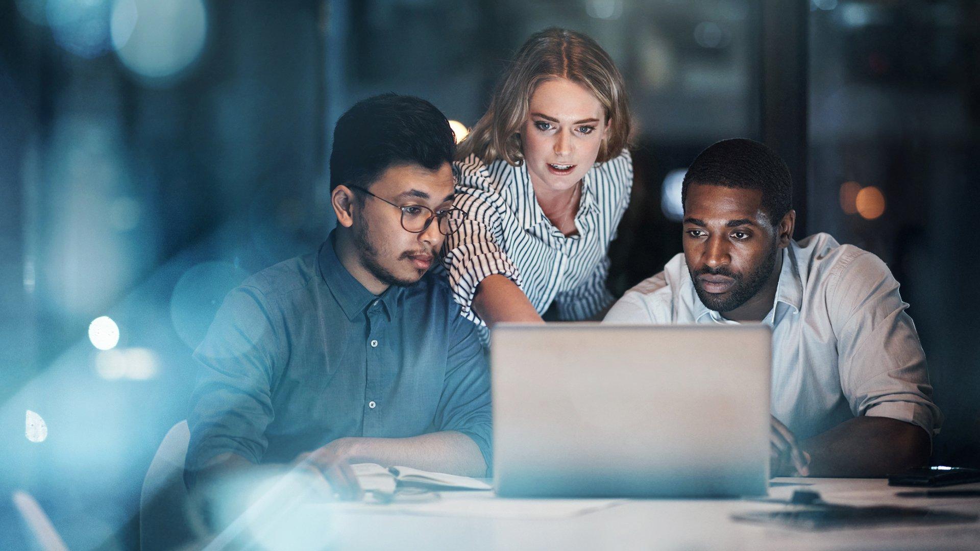 Three marketing and product team leaders collaborating on a computer showing unified digital analytics