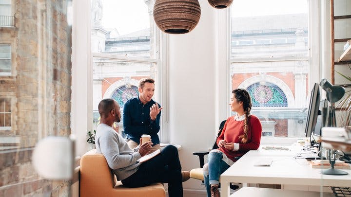 Three workers at a startup engaged in discussion in their office